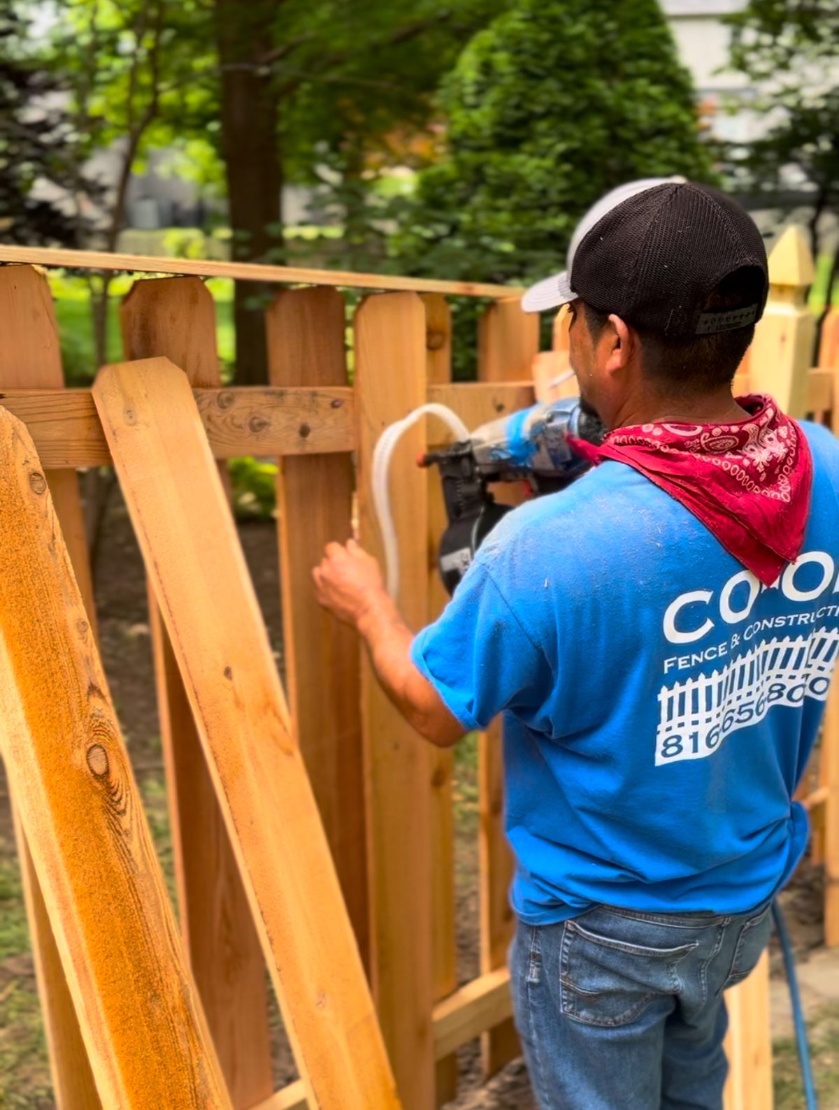 A CO-OP Fence & Construction crew member fastening cedar pickets to a new fence
